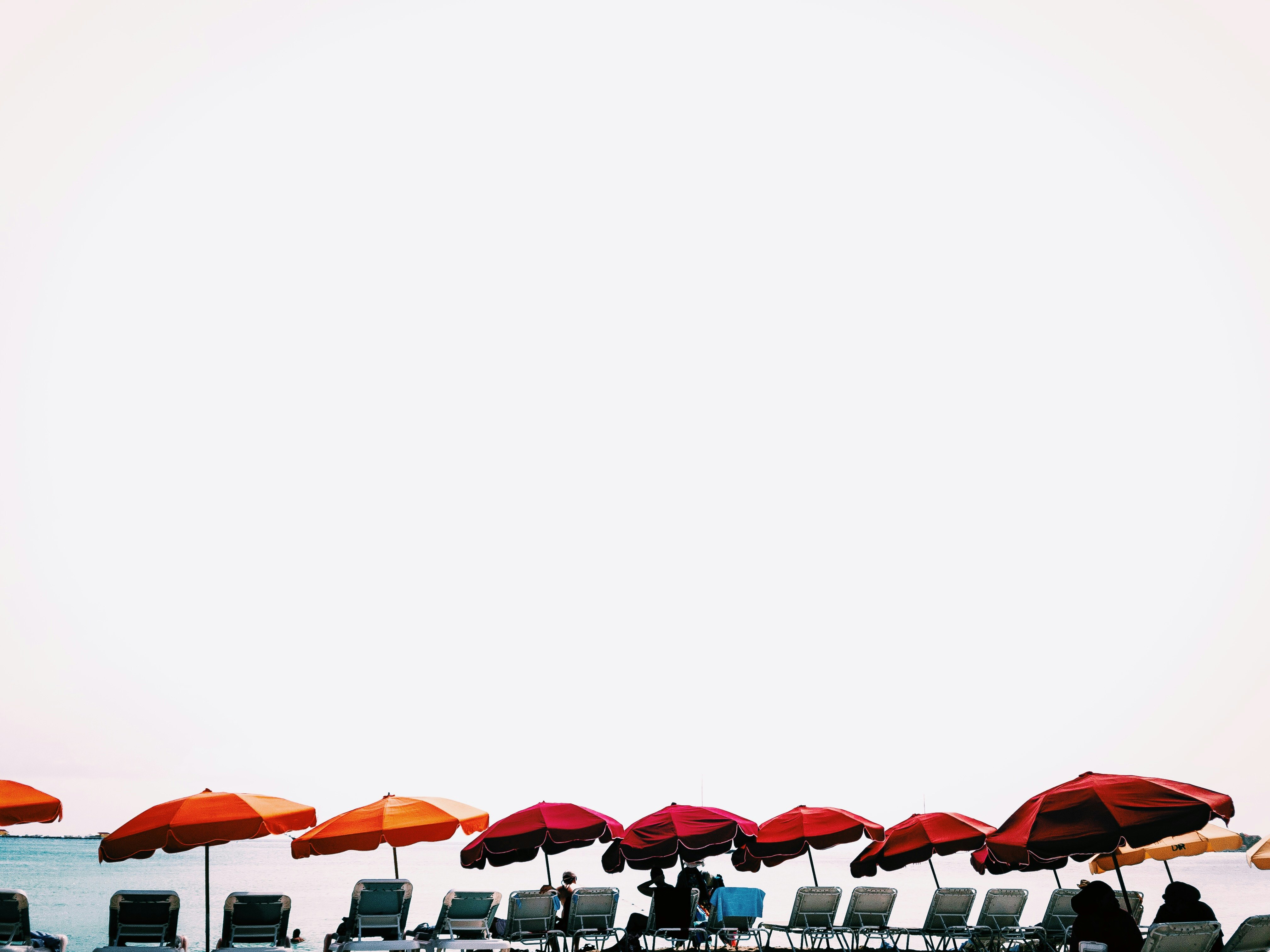 red and orange patio umbrellas in front body of water